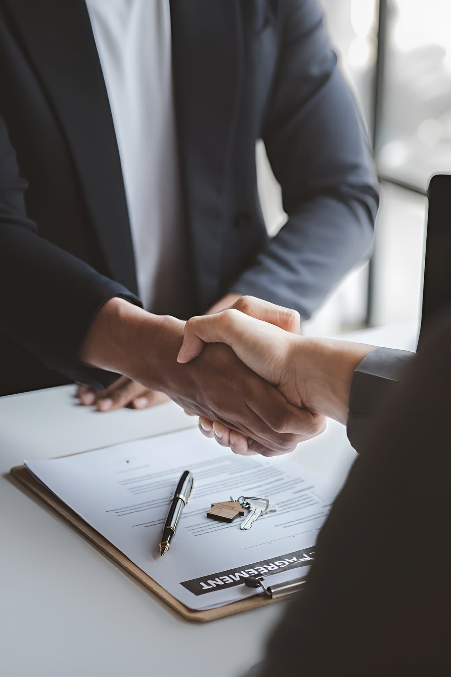 Business handshake above a signed agreement