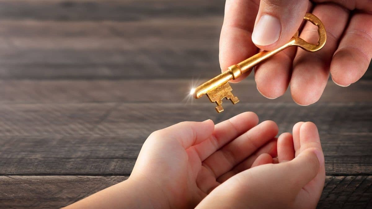 A hand passing a key to a child